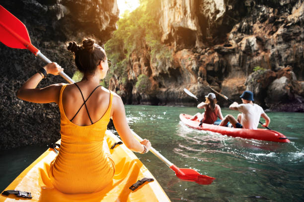 Tropics sea kayaking with friends Beautiful lady and friends walks by kayaks at sea bay between big rocks adventure stock pictures, royalty-free photos & images