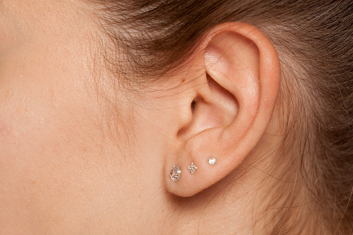 Closeup del oído femenino con tres pendientes photo