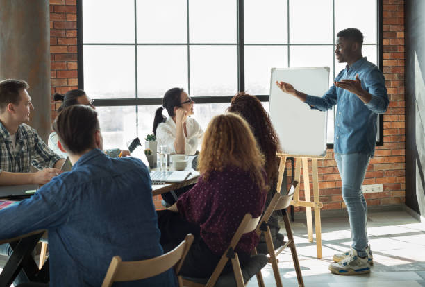 African-american leader lecturing his employees in office African-american team leader is lecturing his employees in loft office using white board, copy space male likeness photos stock pictures, royalty-free photos & images