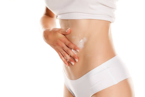 istock Young woman applying cream on her belly on white background 1086277606