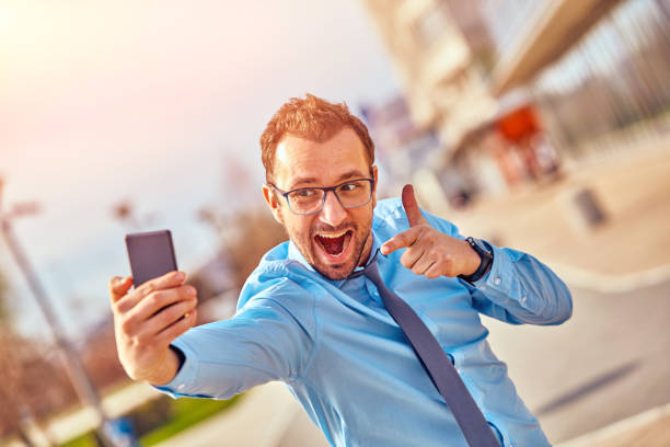 istock Funny businessman with thumbs up while using smartphone outdoors. 1086280318