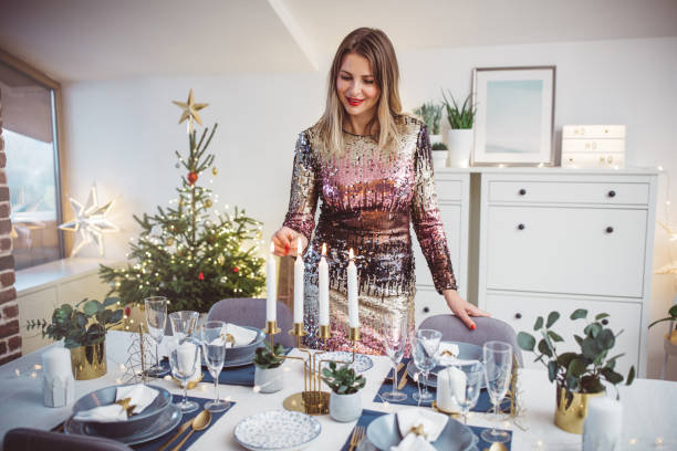 Preparing for Christmas dinner Woman lay the table for family Christmas meal. She arranging everything to be perfect for Christmas. Well dressed. cocktail dress stock pictures, royalty-free photos & images