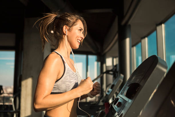 istock Smiling woman running on treadmill in a gym 1086283784