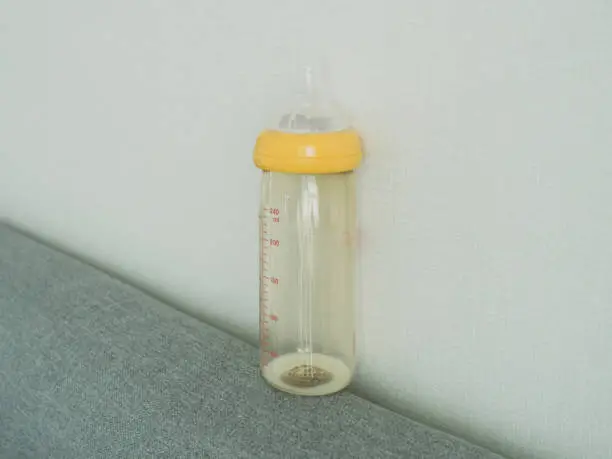 Photo of a baby feeding bottle of little milk on the top of the sofa