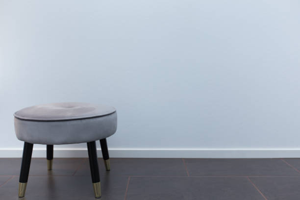 Luxury small chair in front of white wallpaper, standing to the side on limestone floor stock photo