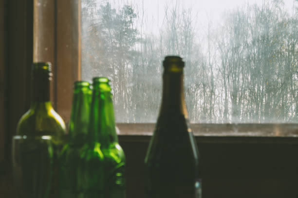 istock Several empty bottles of alcohol near the dirty window. Selective focus. Alcoholism, drunkenness, loneliness and depression concept 1086299550