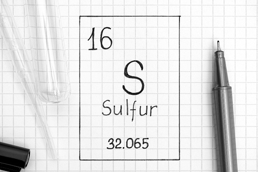 The Periodic table of elements. Handwriting chemical element Sulfur S with black pen, test tube and pipette. Close-up.