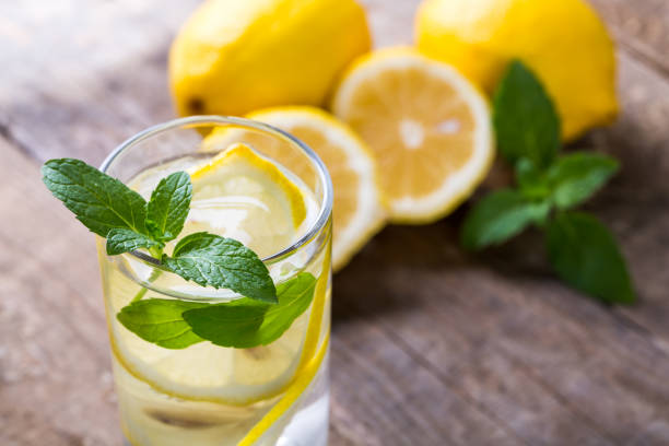 istock Lemon water with fresh lemons and green mint on table 1086311482