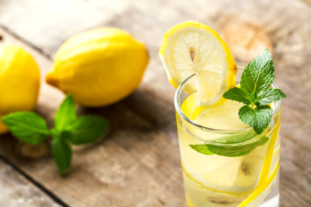 istock Lemon water with fresh lemons and green mint on table 1086311562