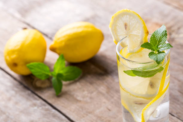 istock Lemon water with fresh lemons and green mint on table 1086311574