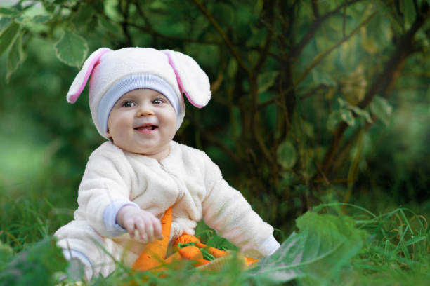 istock Kid in bunny costume sitting on grass in park and smiling 1086330534