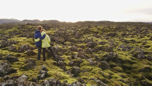 MS Couple standing among moss covered rocks in remote landscape,Iceland