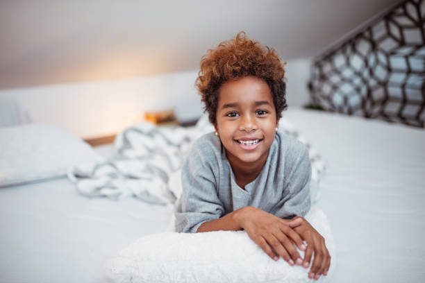 istock Little mixed-race girl lying on bed, looking at camera. 1086347136