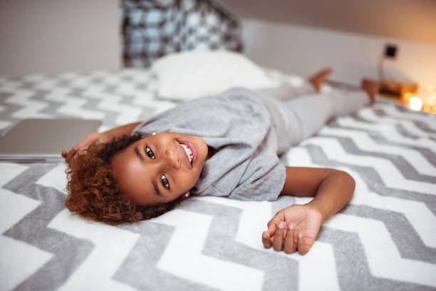 istock Little african american lying on a bed, looking at camera. 1086347298