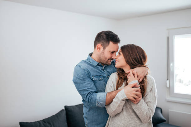istock Smiling young couple hugging while standing together at home. 1086349626