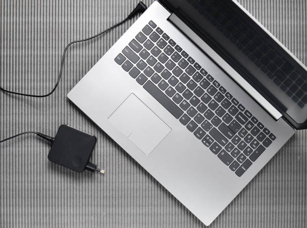 Laptop and charging for a laptop on a gray textured background, top view