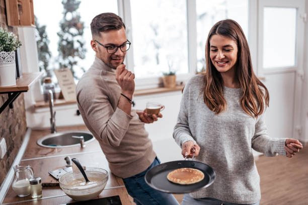 Couple making pancakes at home.
