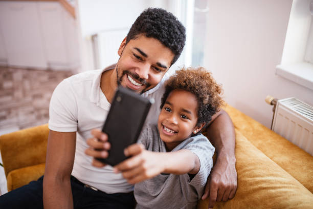 istock Mixed-race father and daughter taking a selfie at home. 1086352296