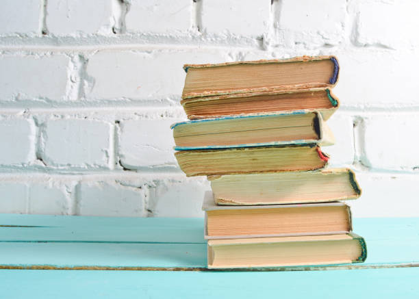 istock Stack of antique books on table against a white brick wall. School concept, education. 1086356452