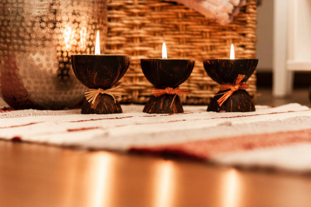 istock Cozy home interior decor, burning candles on a multi-colored rug on the background of a wicker straw box - Image 1086361738
