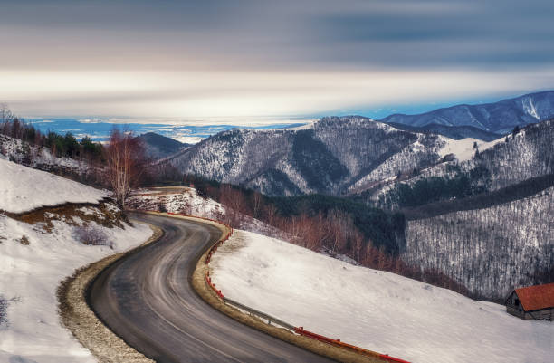 la strada vuota che attraversa le montagne invernali - colortones foto e immagini stock