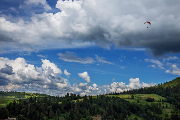 Paraglider flying over mountains during summer day