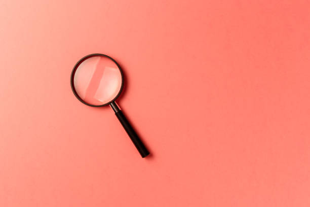 istock Magnifying glass on coral background. Top view. Flat lay. Copy space. New minimal creative concept. Living Coral color of the Year 2019 1086370954