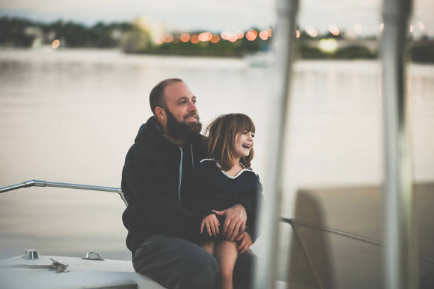 Father and Daughter Boat trip Man with a beard, a father, with a little 5 year old girl, his daughter, are full of happiness and smiles on a boat trip together, they are on a fishing or speed boat and they are affectionate and having an adventure together at dawn or dusk family motorboat stock pictures, royalty-free photos & images