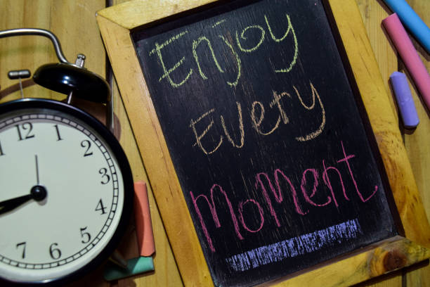 istock Enjoy Every Moment on phrase colorful handwritten on chalkboard 1086376708