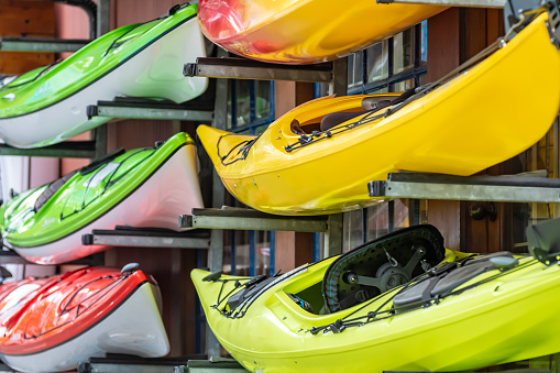 Colorful brightly colored kayaks for rental stacked outside a water sports shop in Vancouver, Canada