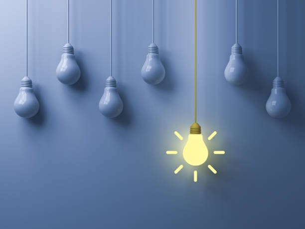 istock Think different concept One hanging yellow idea light bulb standing out from white unlit bulbs on light blue color background leadership and individuality creative idea concepts 1086383466