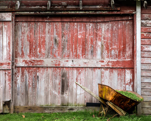 Red barn door with an old, rusted wheel barrow
