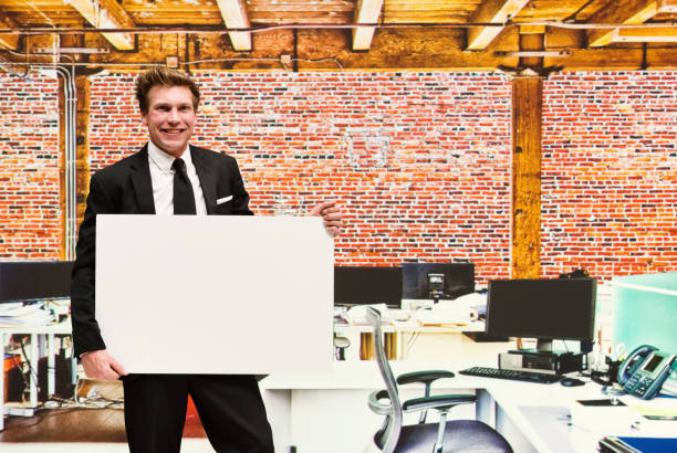 istock Confident businessman standing inside the workplace and holding a white placard 1086404892