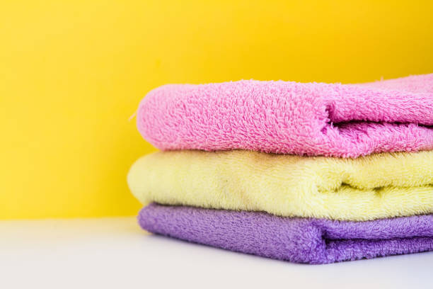 three multi-colored Terry towels have a yellow wall on white background. Copy Space