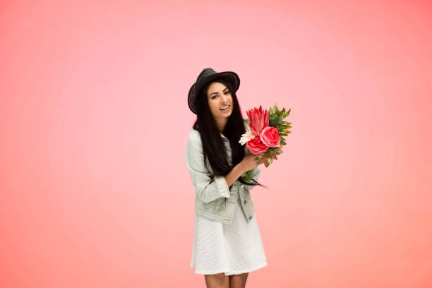 istock Beautiful female on pink background is holding arranged flowers 1086413596