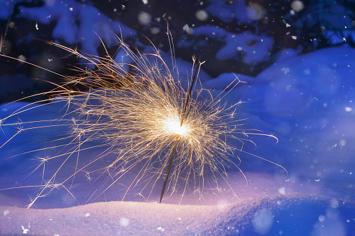 Festive background. Bengal fire, fireworks, spark, snow. Christmas or New Year. Selective focus, close-up.