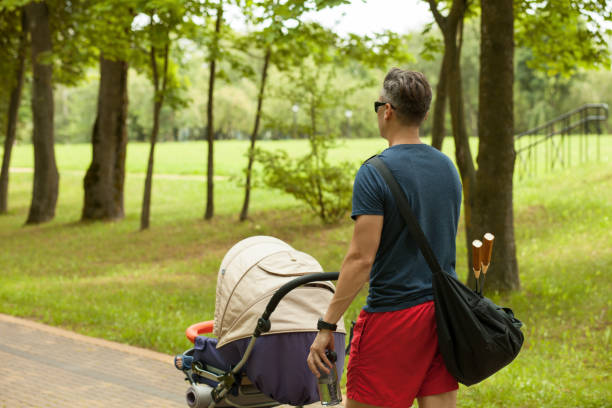 istock 35 year old man with a baby stroller on a walk in the park 1086417044