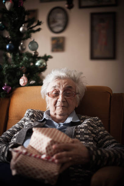 istock Grandma wrapping Christmas gifts by tree . 1086417216
