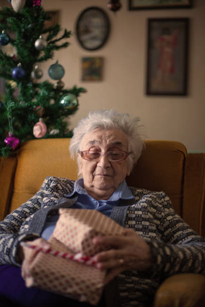 istock Grandma wrapping Christmas gifts by tree . 1086417244