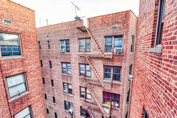 brick apartment condo building roof exterior architecture in fordham heights center, bronx, nyc, manhattan, new york city with fire escapes, windows, ac units in morning, satellite dish, antenna - cheep imagens e fotografias de stock