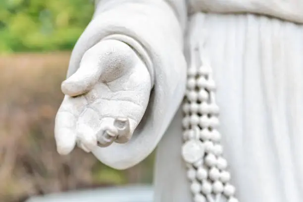 Religious saint Virgin Mary marble white stone statue, sculpture closeup of hand, open palm, fingers, rosary, robe, blessing