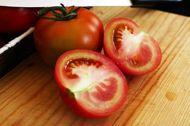 istock tomato cut into two pieces, cut tomatoes on cutting board, knife and tomato, 1086427164