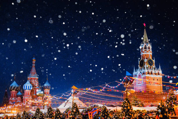 cattedrale di san basilio e torre spasskaya tra decorazioni festive di capodanno sulla piazza rossa a mosca. fiera di natale al cremlino di russia in serata mentre cade la neve. - snow cupola dome st basils cathedral foto e immagini stock