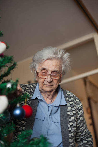 istock Old woman putting ornaments on Christmas tree. 1086433326