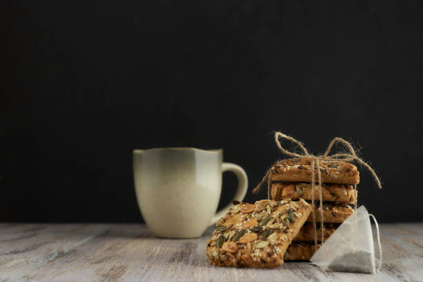 istock A stack of shortbread cookies with different types of nuts to a delicious coffee or tea on a dark wood table. horizontal view. black background. copy space. minimalism with baking. 1086438588