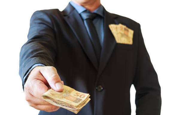 бизнесмен держит деньги бразильца в руках и в кармане костюма. белый фон. - pocket suit close up shirt стоковые фото и изображения
