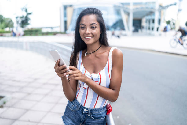 istock Smiling young woman using phone on street 1086454542