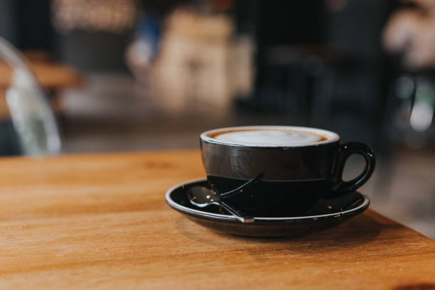 istock hot coffee in black cup on wooden table. 1086483376