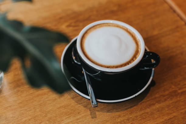 istock hot coffee in black cup on wooden table. 1086484700