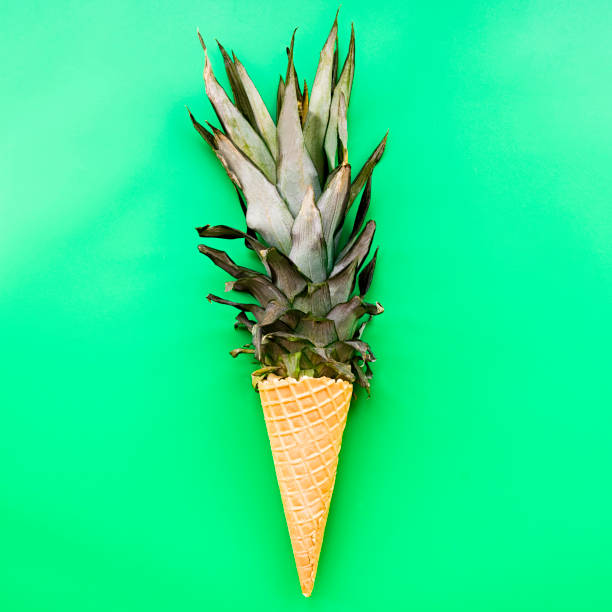 istock Ice cream cone with pineapple leaves on bright green background flat lay top view 1086521700